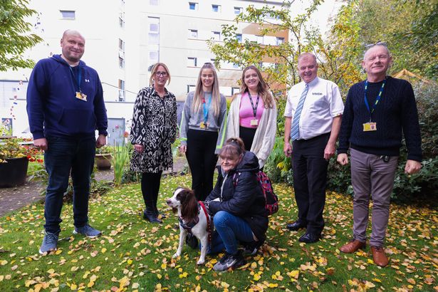 Inreach Officer Dominic Jomfru, Deputy Director Jackie Miles, Team Leader Katie Sherry, Mental Health Specialist, Substance Abuse Officer Annie Johnson, Managing Director Nigel Hughes and Support Officer Andy Topping with user Debbie Melling and her dog Cruella at YMCA Wirral in Birkenhead