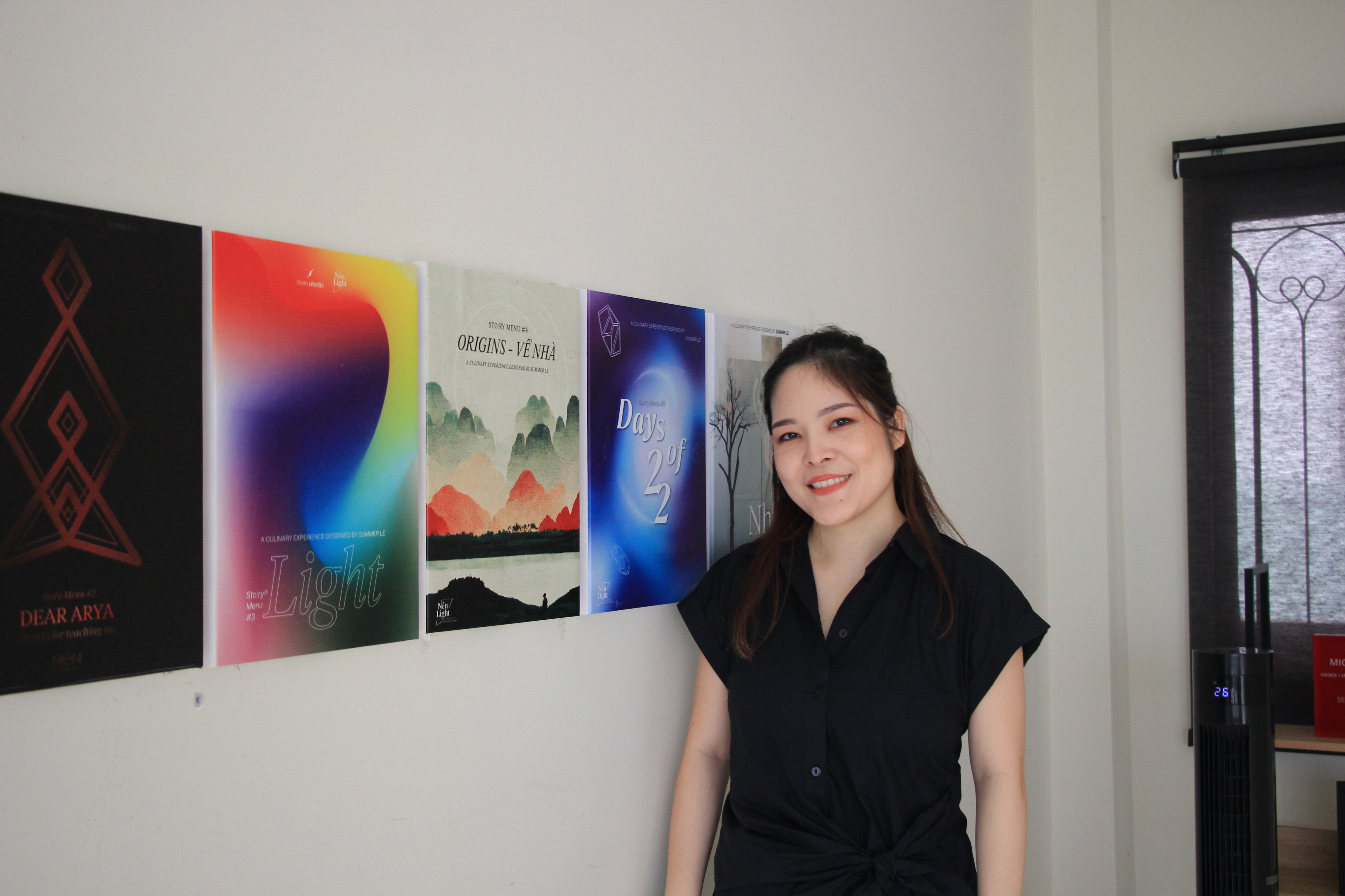 Summer Le poses with the promo photos of Nén's Story Menu concepts displayed at Nén Light Saigon in Ho Chi Minh City. Photo: Dong Nguyen / Tuoi Tre News