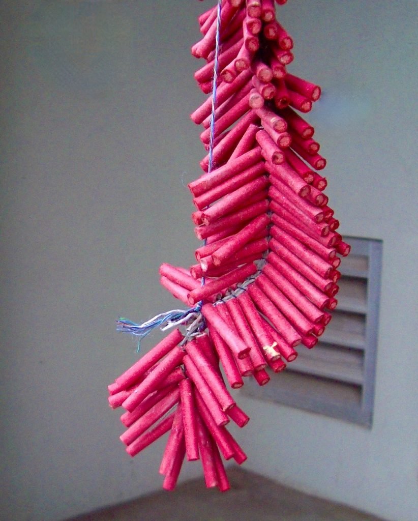 Dozens of red fireworks that hang from a string.
